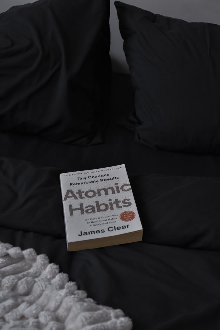 A calming scene with a book on a dark themed bed, conveying a sense of relaxation.